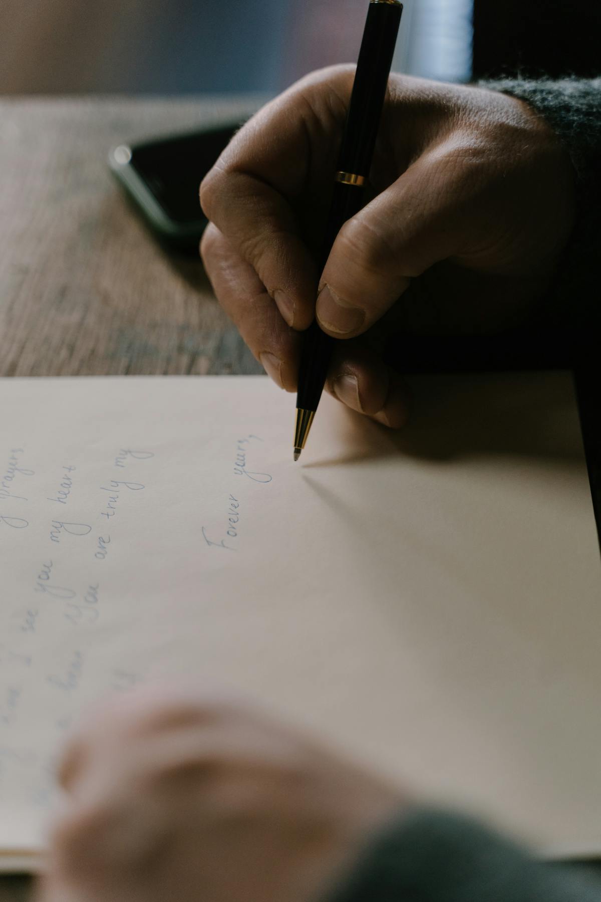 Una persona escribe una carta a mano sobre una mesa